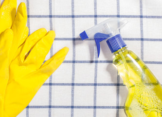 yellow latex gloves with cleaning spray of detergent on white square tablecloth