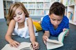 © WavebreakmediaMicro - Girl and boy reading books at library in school