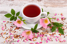 Cup Of Tea With Wild Rose Flower On Old Rustic Wooden Background