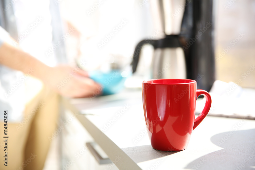 Red cup of coffee and young man on background