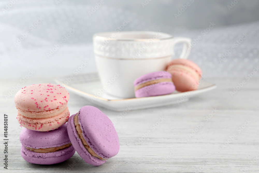 Tasty macaroons with tea on wooden table