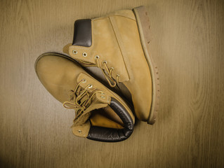 Pair of old yellow working boots Isolated on wood background