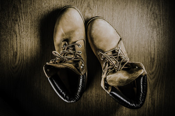 Pair of old yellow working boots Isolated on wood background