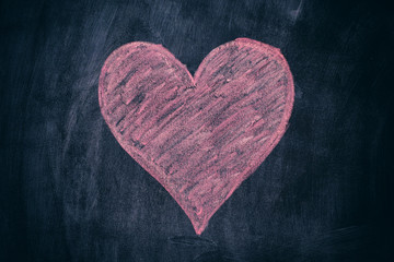 Pink heart shape on black chalkboard background