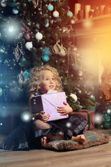 Little girl stands with a gift on the pillow  