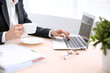 © rogerphoto - Close up of business woman  hands  with a cup of coffee is sitting at the table and typing on a laptop computer in the white colored office .