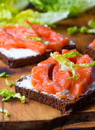 Sandwich With Cereals Black Bread And Salmon On Wooden Board