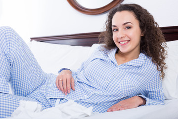 Wall Mural - Brunette female lounging in bed and smiling