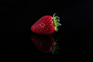 One juicy strawberry on black background