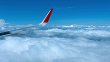 Dramatic View Of  A Commercial Airliner's Wing, Passing Over A Layer Of Puffy, White Clouds, In Timelapse.