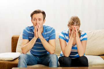 Worried couple after fight sitting on sofa