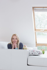 Beauty confident woman looking sideways sitting on a couch at ho