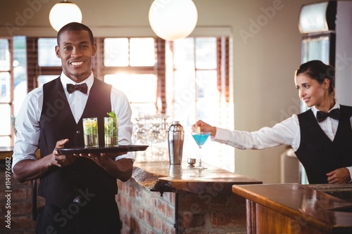 Fotomural Bartender holding a serving tray with two cocktail glass