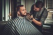 © Nejron Photo - Confident man visiting hairstylist in barber shop.