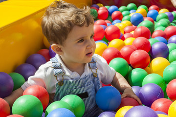 Baby boy having fun playing in a colorful plastic ball pool