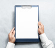 © Alexandr Bognat - Hand holding blank clipboard with white a4 paper design mockup. Clear document holder mock up template hold arm. Clip board notepad surface display front. Checklist tablet plan file presentation.