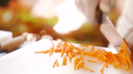 Wall Mural - Knife quickly cuts carrot. Hand takes shredded carrot. Important ingredient for healthy salad. Fast and accurate moves.