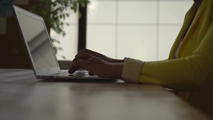 Poster - Women's hands computing on the laptop at working place. Mixed race model wearing in casual stylish yellow jacket.