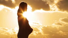 Silhouette Of A Pregnant Woman In The Sunset Sky