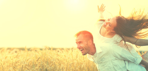 Happy couple having fun outdoors on wheat field over sunset