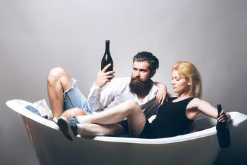 young couple in bath with wine bottles