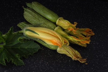 Wall Mural - Green organic zucchini stack with blossoms closeup background, dark photography.