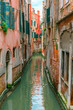 Colorful narrow lateral canal in Venice with docked boat, Italy