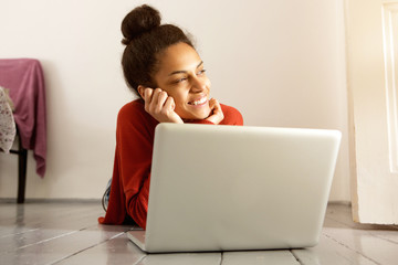 Wall Mural - Young woman with laptop lying on floor and thinking