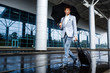 © Cookie Studio - Picture of  young redhaired businessman holding black umbrella and suitcase walking in rain at airport