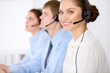 © rogerphoto - Call center operators. Young beautiful business woman in headset.  Male phone operator in headset at the background.