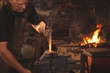 Blacksmith Working On A Heated Iron Rod In Workshop
