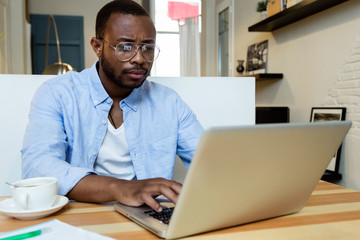 Handsome young black man working with laptop at home.