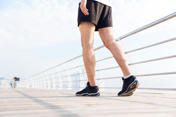 Closeup of young man legs walking on wooden terrace