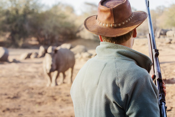 ranger with firearm face to face with rhino