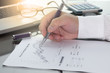 © thbangkok - Businessman or fund manager review Mutual Fund information with performance line graph and benchmark with pen calculator and computer laptop.
