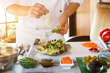 Wall Mural - Male hands make salad. Salad plate on cooking board. Don't distract the cook. Need more ingredients.