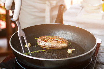 Wall Mural - Meat and herb on pan. Hand with meat fork. Add some garlic and herbs. Preparation of duck steak.