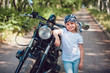 © kanashkin - Little girl in a white T-shirt and bandana standing near  motorcycle