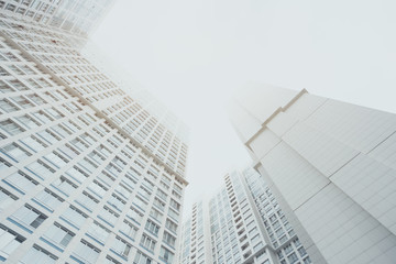 White contemporary residential skyscraper apartment building in Moscow on a cloudy day, two housing body, regular windows, view from bottom