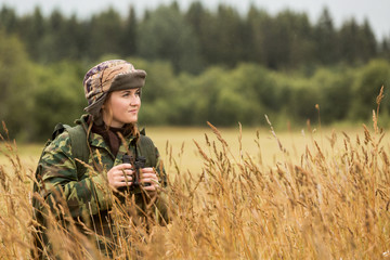 woman hunter, autumn rain, girl looks through binoculars