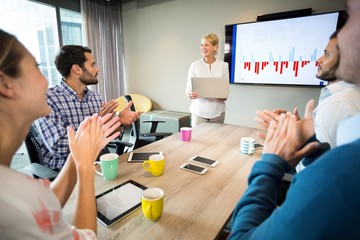 coworkers applauding a colleague after presentation