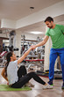 © sasamihajlovic - Personal trainer helping girl to stand up in the gym