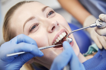 Wall Mural - close up of dentist treating female patient teeth