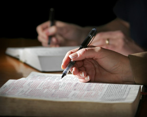 Couple Studies the Bible - focus point on woman's foreground hand.