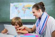 Smiling teacher assisting boy using digital tablet
