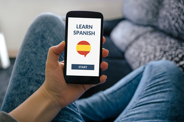 Hand holding smart phone with online learn spanish concept on screen. All screen content is designed by me.