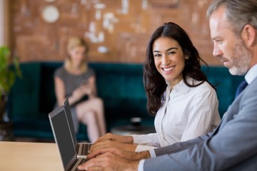 Business colleagues sitting on table and using laptop