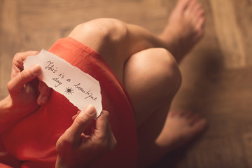 Woman holding a paper note with a motivational text