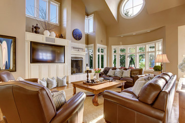 Large living room interior design with high vaulted ceiling and leather sofa set.