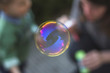© GENETTICA - Soap bubble reflecting sunset colors and woman with little kid in the background.